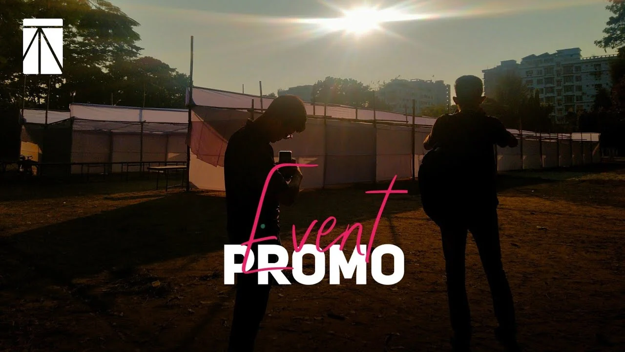 Video still at sunset: silhouettes of two people in front of a row of white stalls, with the words Event Promo and a small white TECHious logo in the corner.