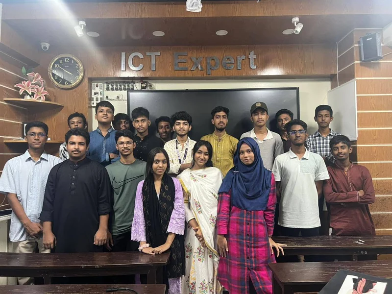 About twenty TECHious members pose for a group photo in a classroom under the ICT Expert sign, Cumilla.