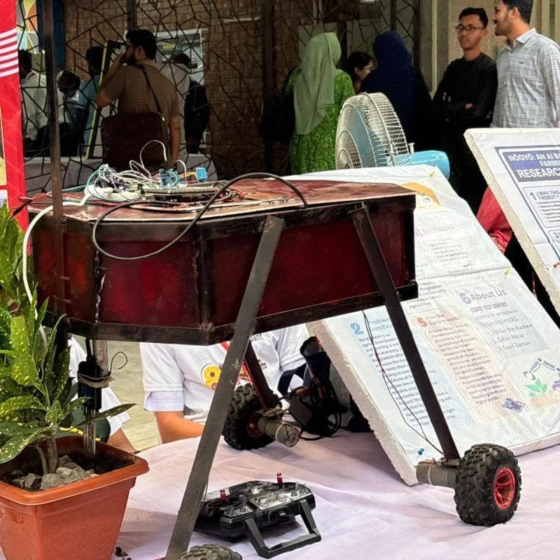 A student-built wheeled robot with a red body, exposed wiring and a remote controller is displayed on an exhibition table at WICE 2026.